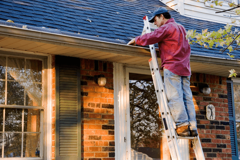 Man on Laddder Cleaning Gutters | One Stop Home Improvement Shop